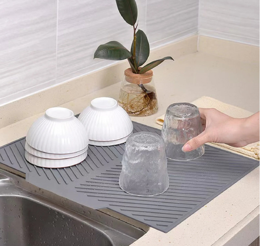 Drainage silicone pad on a kitchen counter with bowls and glasses.